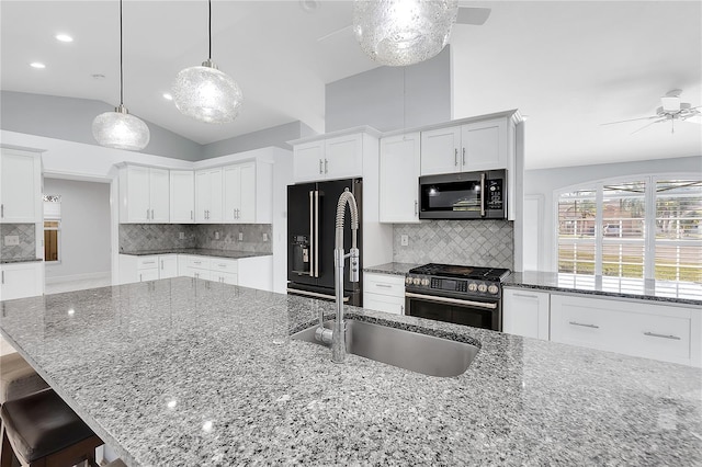 kitchen with lofted ceiling, tasteful backsplash, high quality appliances, pendant lighting, and white cabinets