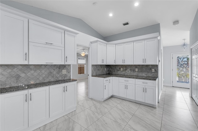 kitchen featuring lofted ceiling, dark stone counters, and white cabinets