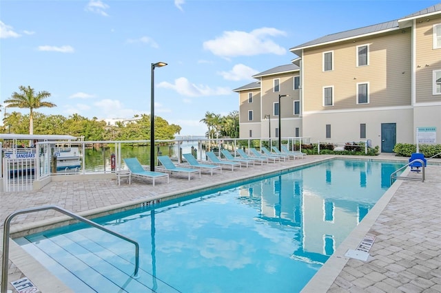 view of swimming pool featuring a water view and a patio area