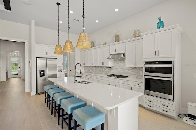 kitchen featuring white cabinetry, an island with sink, sink, hanging light fixtures, and stainless steel appliances