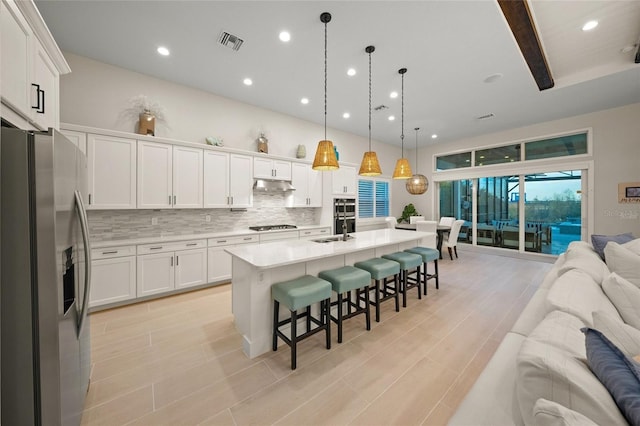 kitchen featuring decorative light fixtures, a kitchen island with sink, stainless steel fridge with ice dispenser, and white cabinets