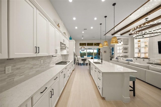 kitchen featuring light stone counters, sink, decorative light fixtures, and white cabinets