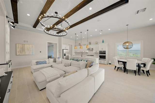 living room featuring beam ceiling, a chandelier, and sink