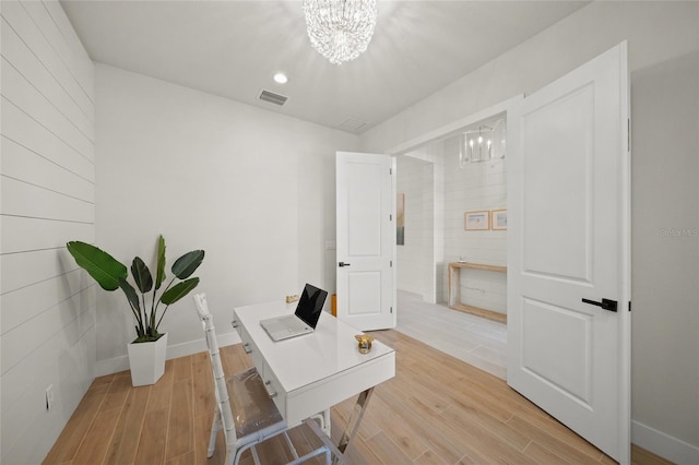 home office with light wood-type flooring and a chandelier