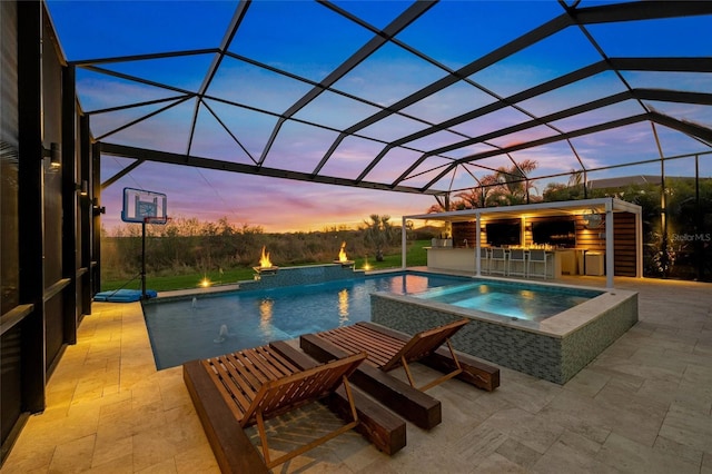 pool at dusk featuring a bar, a lanai, a patio, and an in ground hot tub