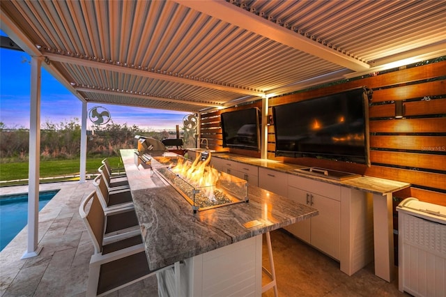 view of patio with an outdoor kitchen and a fire pit