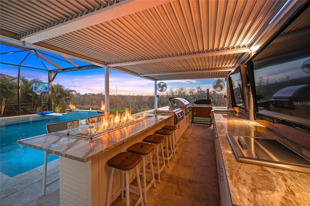 view of patio / terrace with a bar, an outdoor kitchen, and an outdoor fire pit