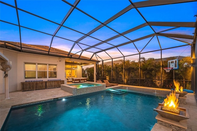 pool at dusk with an in ground hot tub, an outdoor fire pit, a lanai, and a patio