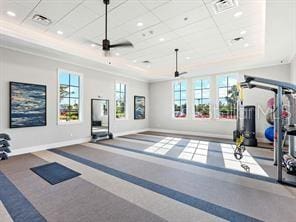 workout room with a tray ceiling and ceiling fan