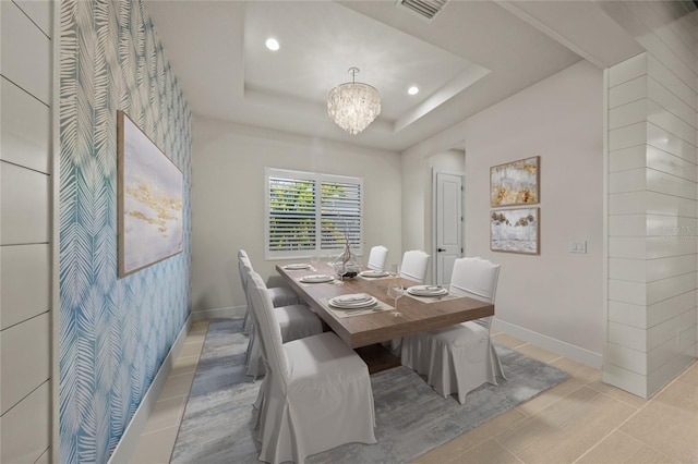 tiled dining space featuring a raised ceiling and a notable chandelier