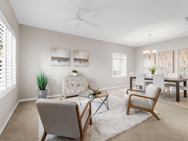 carpeted living room featuring ceiling fan with notable chandelier