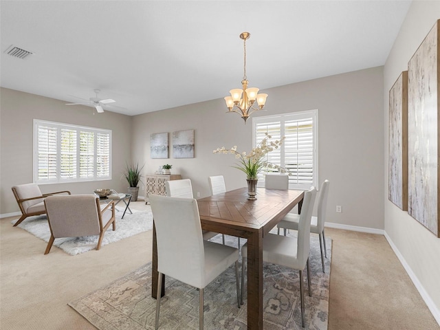 carpeted dining space with ceiling fan with notable chandelier and a wealth of natural light