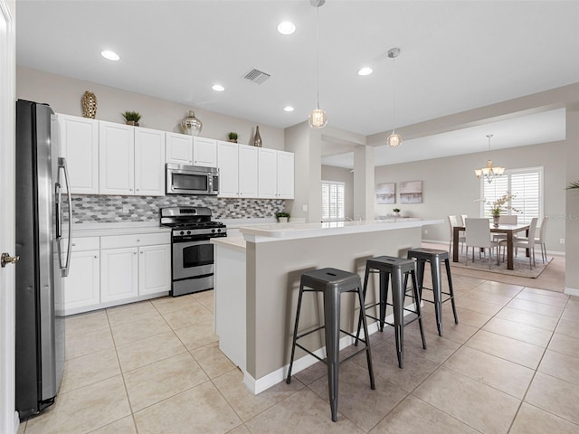 kitchen featuring a breakfast bar area, a center island, light tile patterned floors, pendant lighting, and stainless steel appliances