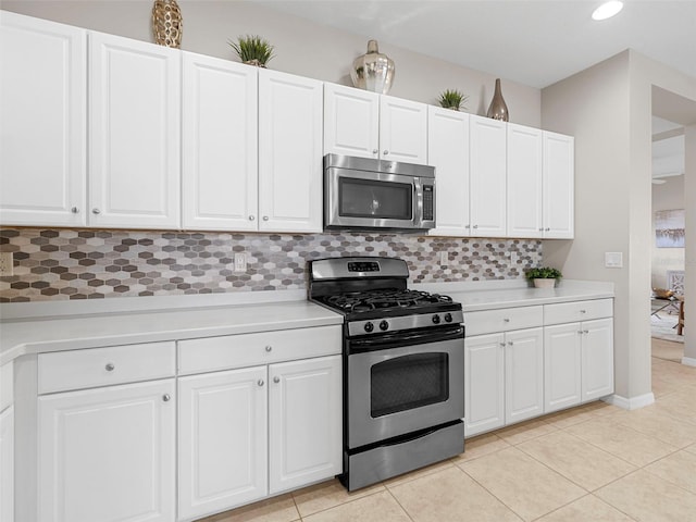 kitchen featuring light tile patterned flooring, appliances with stainless steel finishes, white cabinets, and backsplash