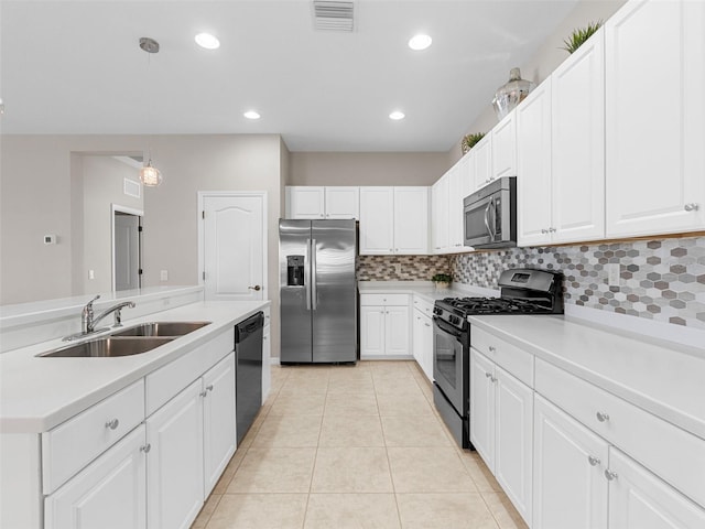 kitchen with stainless steel appliances, white cabinetry, sink, and decorative light fixtures