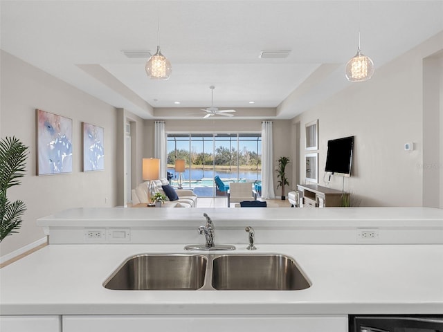 kitchen with sink, pendant lighting, and a tray ceiling