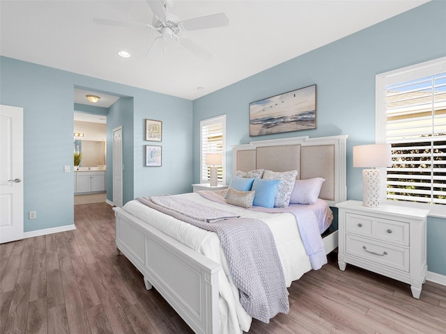 bedroom with ceiling fan, ensuite bath, and light hardwood / wood-style flooring