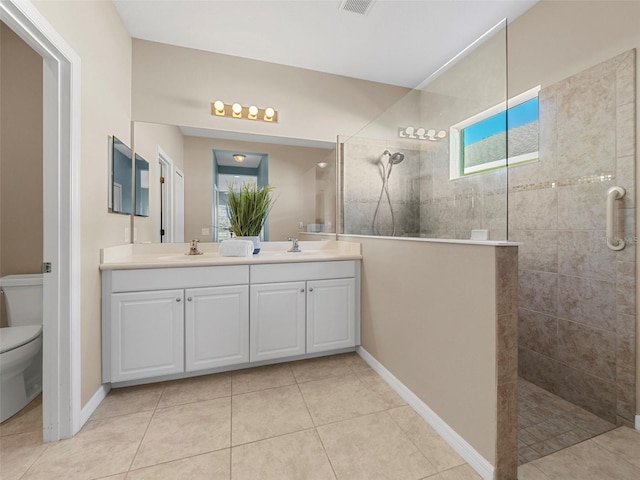 bathroom featuring tile patterned flooring, vanity, a tile shower, and toilet