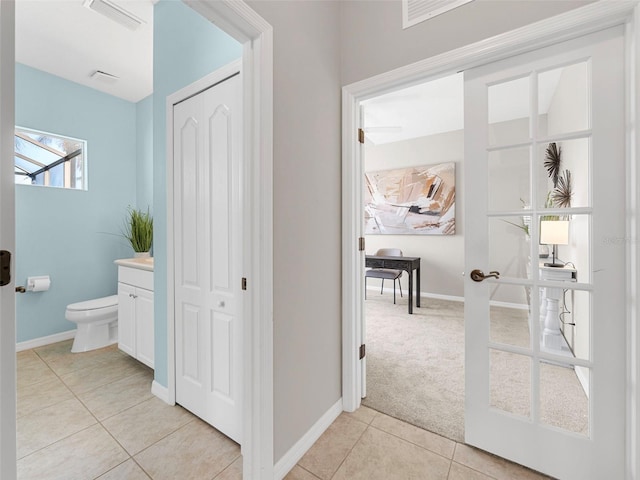 bathroom with tile patterned flooring, toilet, vanity, and french doors