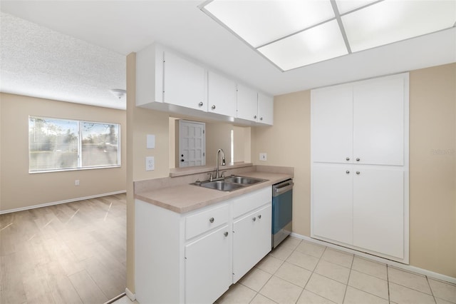 kitchen with sink, a textured ceiling, white cabinets, and dishwasher