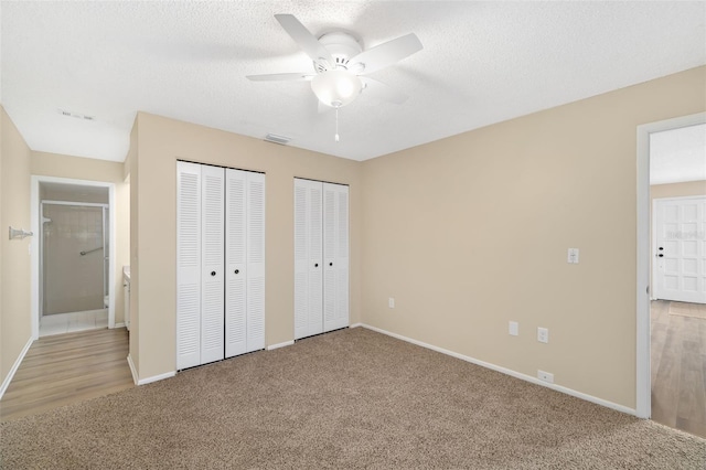 unfurnished bedroom with two closets, ceiling fan, and carpet