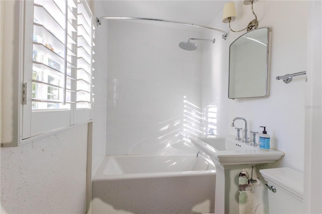 bathroom with tiled shower / bath combo and toilet