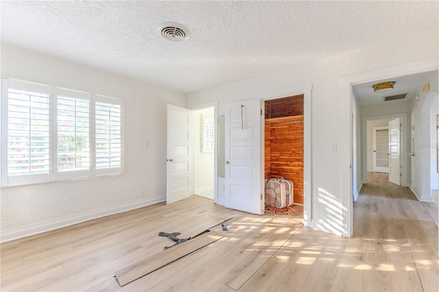 unfurnished bedroom featuring a textured ceiling, light hardwood / wood-style floors, and a closet