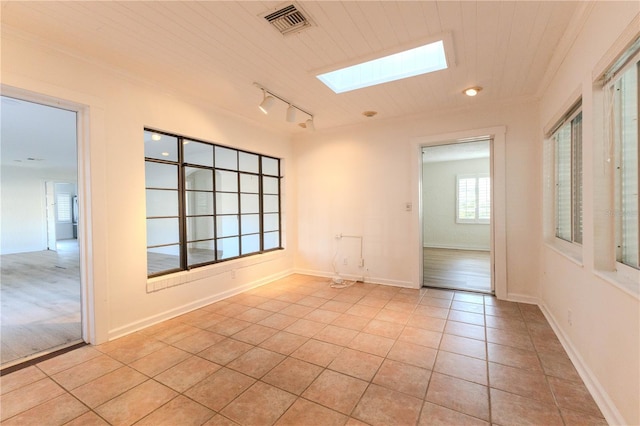 tiled empty room with wood ceiling, rail lighting, and a skylight