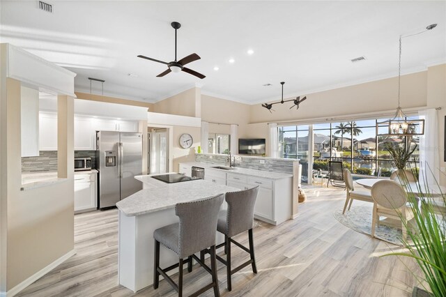 kitchen with sink, light stone counters, stainless steel appliances, kitchen peninsula, and white cabinets