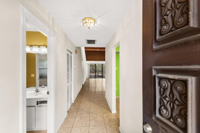 corridor with a wealth of natural light, sink, and light tile patterned floors