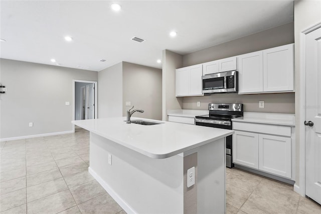 kitchen featuring sink, light tile patterned floors, white cabinetry, stainless steel appliances, and a center island with sink