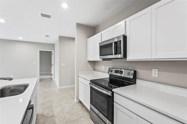 kitchen with white cabinetry, appliances with stainless steel finishes, sink, and light tile patterned floors