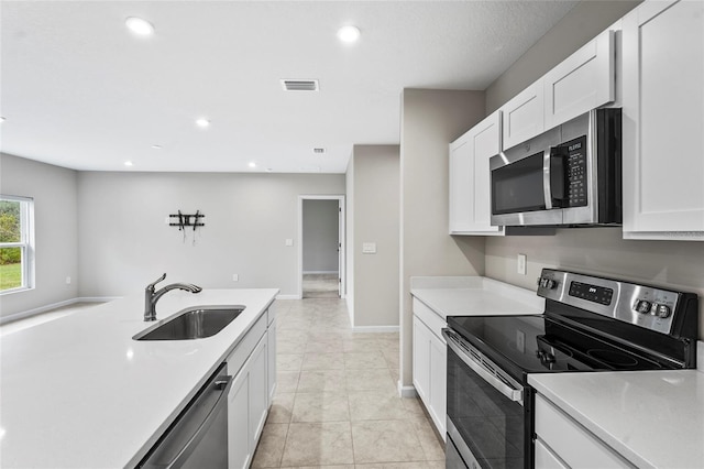 kitchen with light tile patterned flooring, appliances with stainless steel finishes, sink, and white cabinets