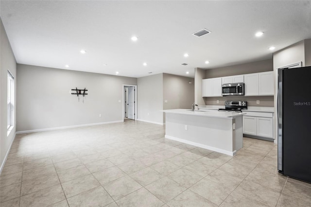 kitchen featuring appliances with stainless steel finishes, white cabinetry, sink, a kitchen island with sink, and light tile patterned floors