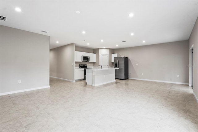 kitchen featuring sink, light tile patterned floors, appliances with stainless steel finishes, white cabinetry, and a center island with sink