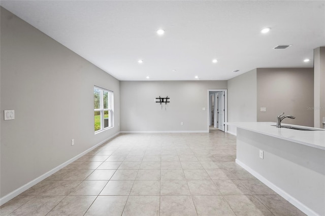 unfurnished living room with light tile patterned flooring and sink