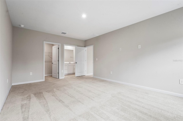 unfurnished bedroom featuring a spacious closet, light colored carpet, and a closet