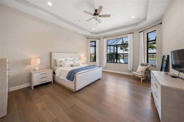 bedroom featuring a tray ceiling, dark wood-type flooring, and ceiling fan