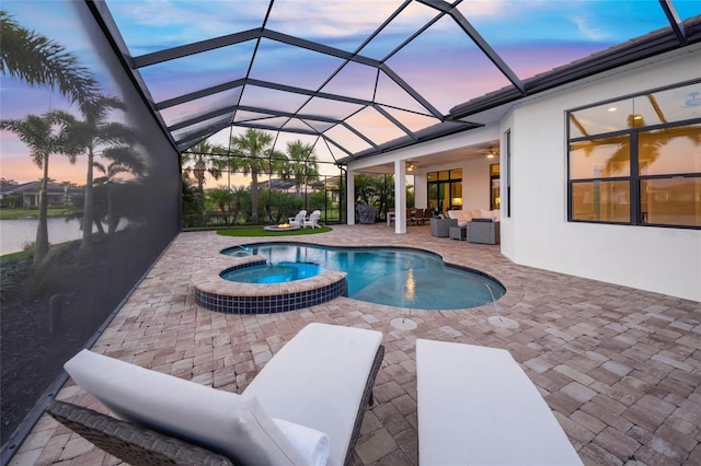 pool at dusk featuring an in ground hot tub, a lanai, a patio area, and outdoor lounge area