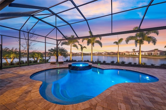 pool at dusk with a patio area, an in ground hot tub, a water view, and glass enclosure