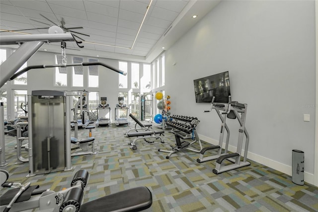 exercise room featuring a towering ceiling and carpet flooring