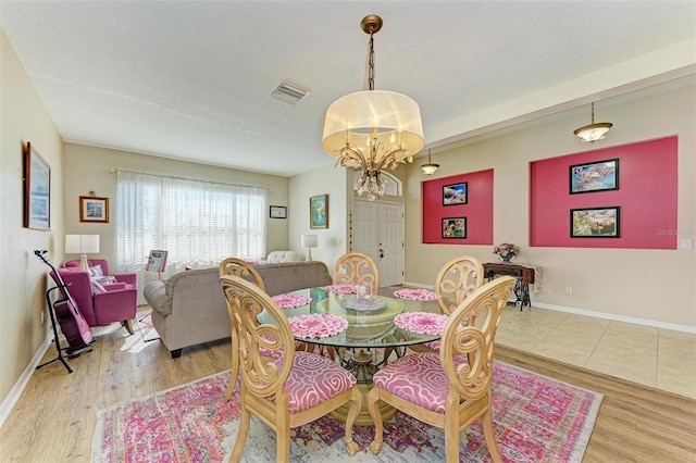 dining room with light hardwood / wood-style flooring, a chandelier, and a textured ceiling