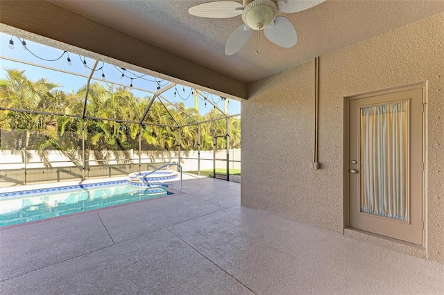 view of pool featuring ceiling fan, an in ground hot tub, glass enclosure, and a patio area