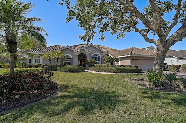 mediterranean / spanish-style home featuring a garage and a front yard