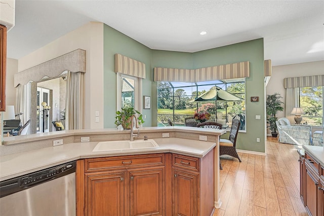 kitchen with light hardwood / wood-style floors, dishwasher, sink, and a textured ceiling