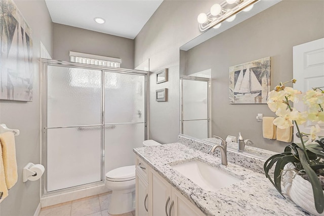 bathroom featuring vanity, a shower with shower door, tile patterned floors, and toilet