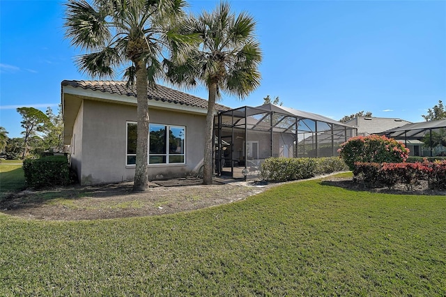 back of property with a yard and glass enclosure