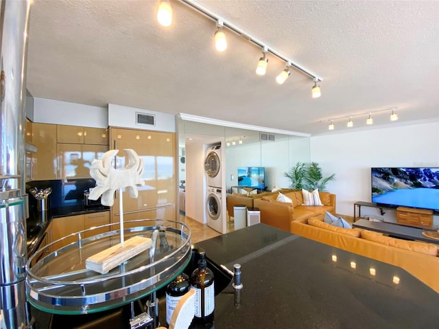 kitchen with stacked washer / dryer and a textured ceiling