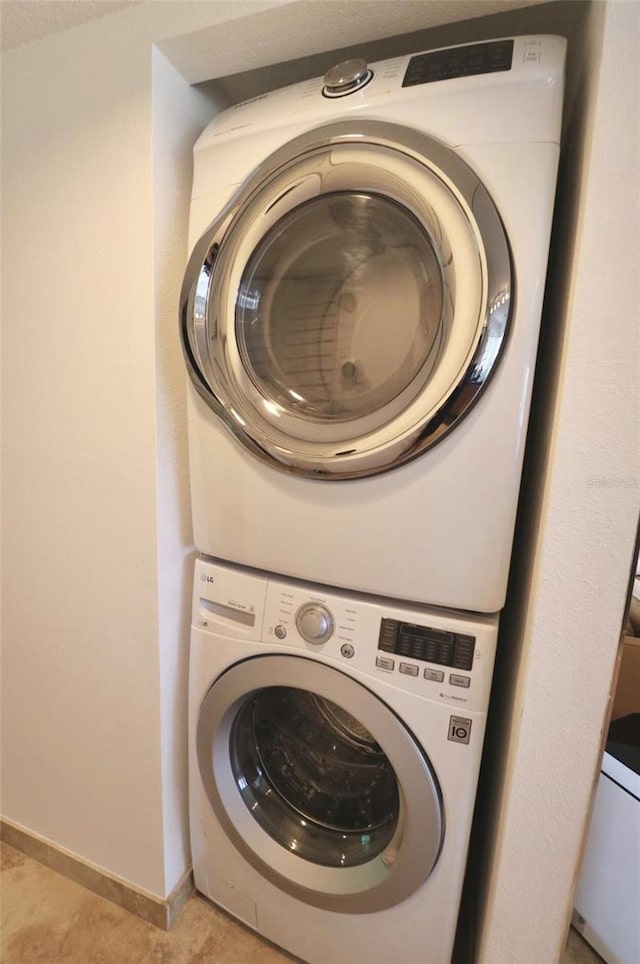 laundry area with light tile patterned floors and stacked washing maching and dryer