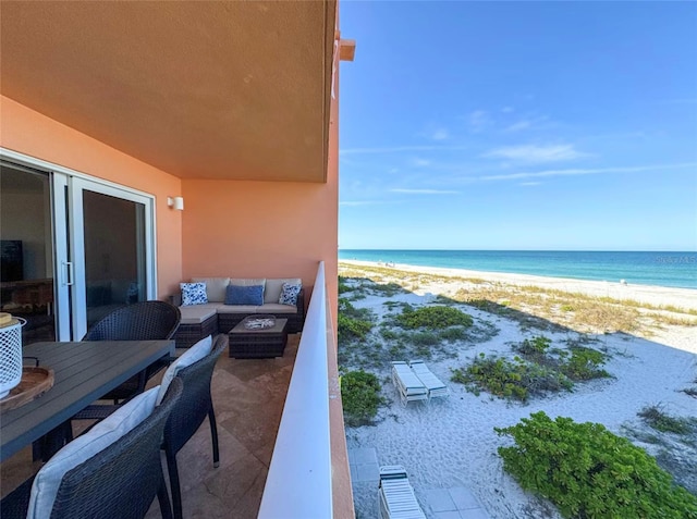 balcony with a view of the beach, a water view, and an outdoor living space